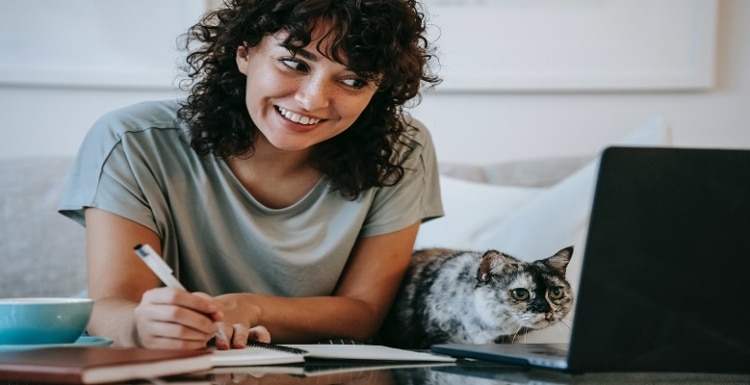 Vrolijke vrouw achter laptop met zomers weer en een kat